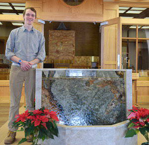 Jake Nelson stands next to new St. Michael baptismal font